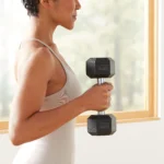 A young woman engaged in a workout session, lifting a hex dumbbell to enhance her fitness and strength training.